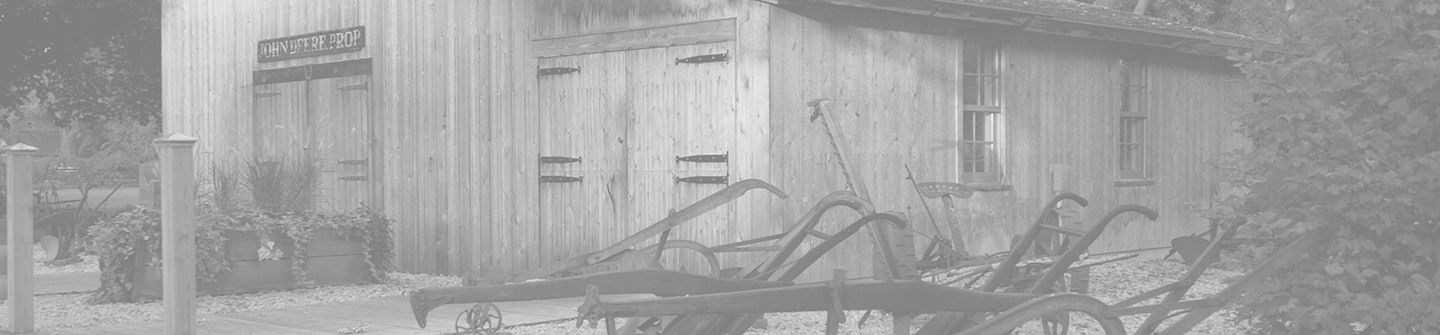 Tonirana crno-bela fotografija rekonstrukcije istorijske lokacije prvobitne kovačke radnje Džona Dira na zelenoj pozadini