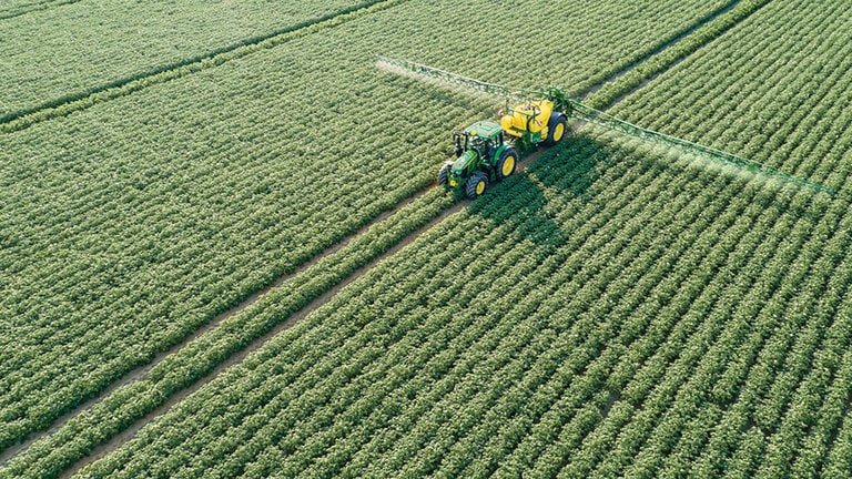 John Deere 6M Series traktor vuče M700 prskalicu u polju s krompirom