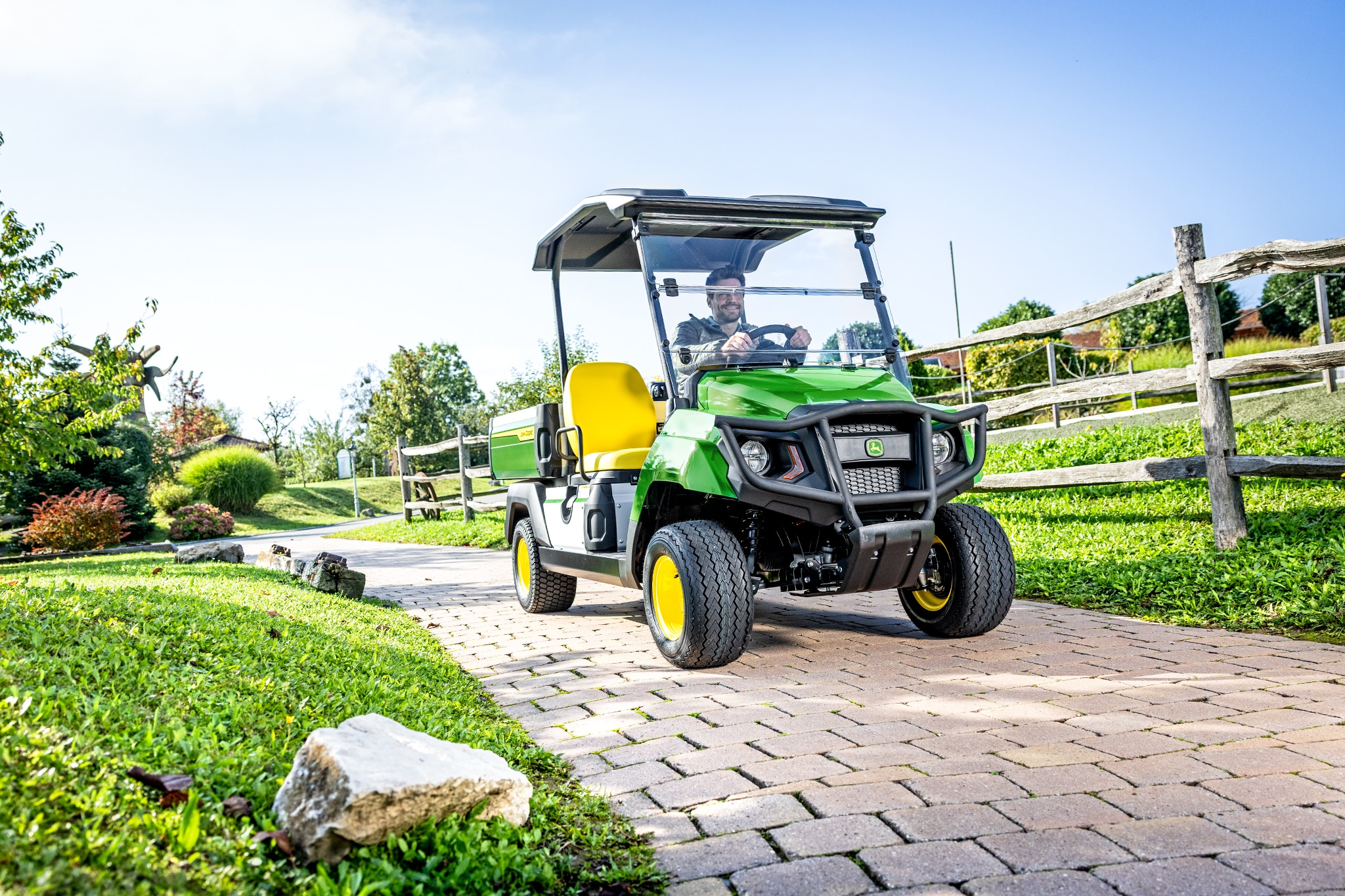 Komunalno vozilo Gator GS koje se vozi asfaltiranom stazom u uređenom prostoru Komunalno vozilo Gator GS koje se vozi asfaltiranom stazom u uređenom prostoru