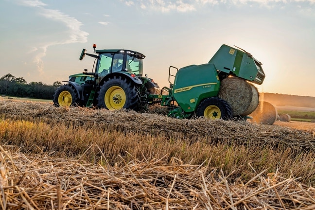 John Deere F442M balirka koju vuče traktor John Deere 6M izbacuje balu sena