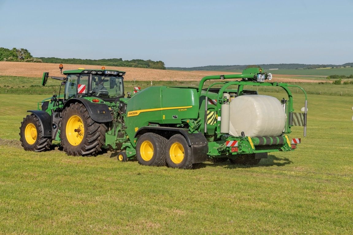 John Deere C442R balirka s mehanizmom za omotavanje koju vuče John Deere 6R 185 pravi silažne bale velike gustine
