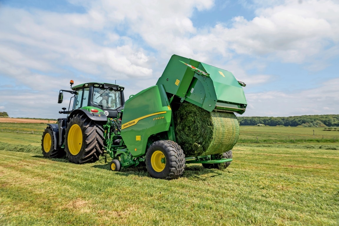 John Deere F442M balirka koju vuče traktor John Deere 6M izbacuje balu trave