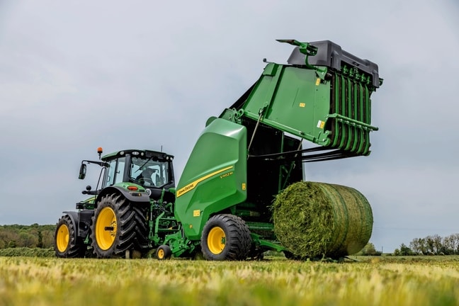 John Deere V462M balirka koju vuče traktor John Deere 6M izbacuje balu trave