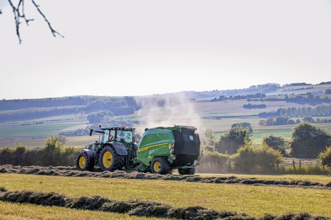 John Deere V462R koju vuče traktor John Deere 6R 185 balira seno